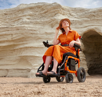 Elektrischer Rollstuhl für Outdoor-Nutzung, Frau im faltbaren E-Rollstuhl in einer natürlichen Felslandschaft, barrierefreie Mobilität und Reisen.
